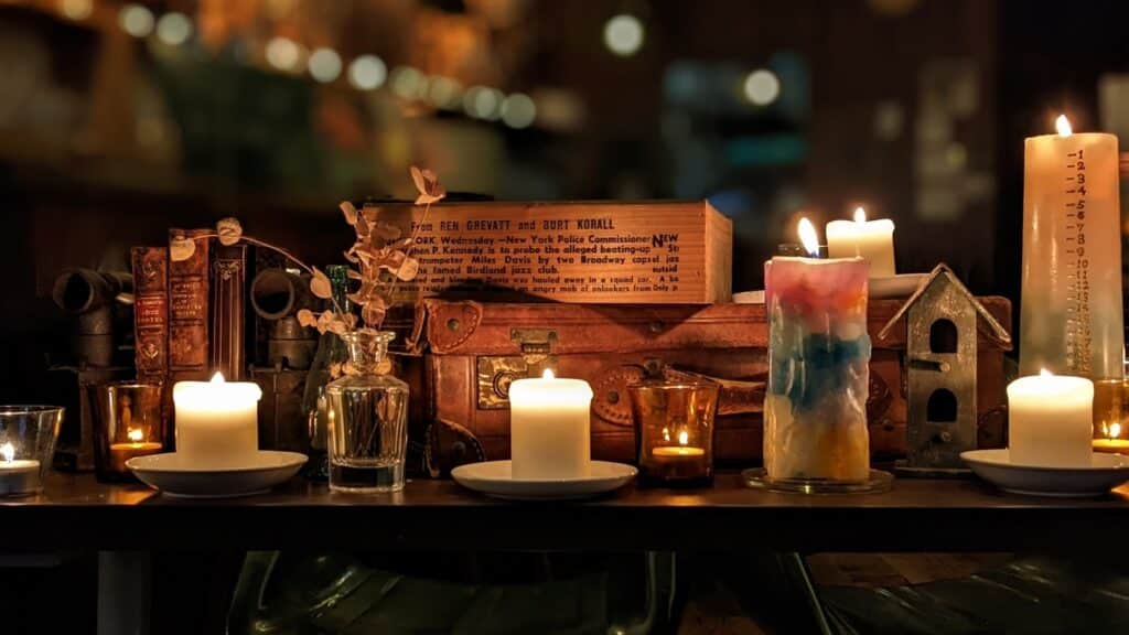 日本語:
アンティークの本やトランクと共に並べられたキャンドルが灯る、落ち着いた雰囲気のディスプレイ:不安を和らげる瞑想