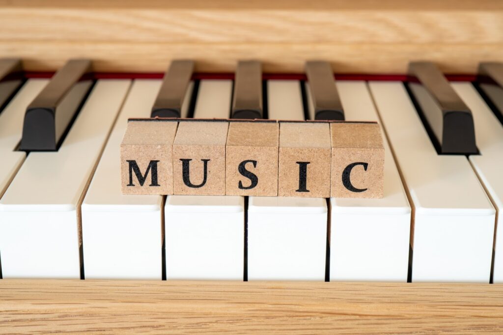 ピアノの鍵盤の上に置かれた木製のブロックが「MUSIC」と並べられている:睡眠のための穏やかな音楽