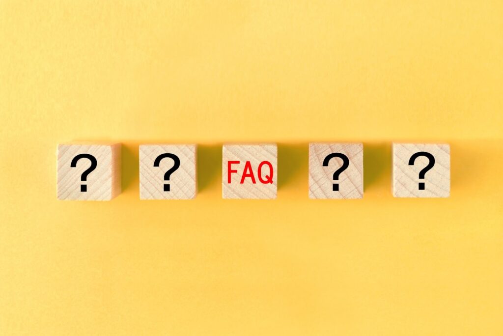黄色い背景に、中央に「FAQ」と書かれた木製ブロックと、両側に疑問符が描かれたブロックが並んでいる:睡眠のための穏やかな音楽
