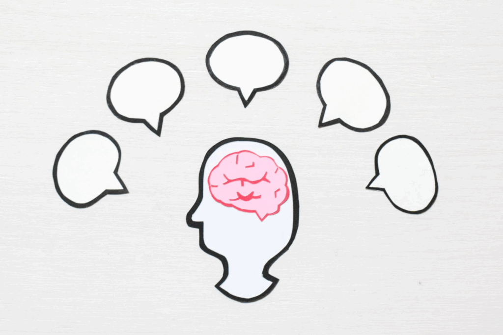An illustration of a human profile with a brain drawn inside the head. Several speech bubbles are arranged around it, symbolizing overflowing thoughts and ideas.:Subconscious