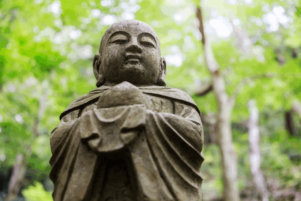 森の中に立つ石の地蔵菩薩像。両手を胸の前で合わせ、穏やかな表情を浮かべている。：不安障害