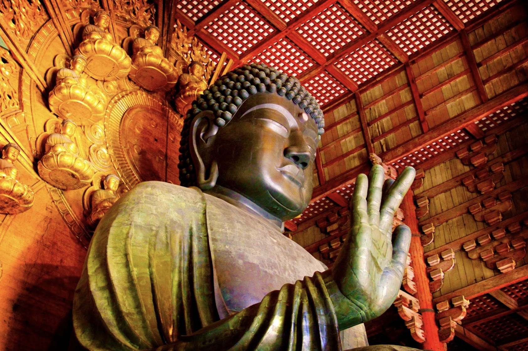 奈良・東大寺の大仏（盧舎那仏）の堂々とした姿。右手を上げて施無畏印を示し、背後には黄金に輝く仏像装飾が並び、荘厳な雰囲気を放っている。：日本の瞑想