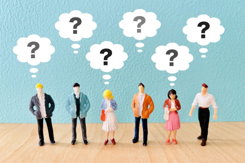 6人のミニチュア人形が並び、頭の上に「？」マークの吹き出しが描かれている。疑問や迷いを表現したイメージ：10分間の瞑想