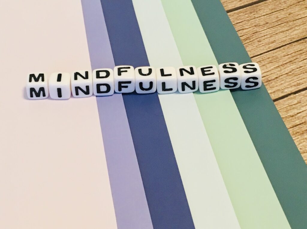 The word "MINDFULNESS" spelled out with cube blocks on a colorful striped background : Mindfulness What Is It