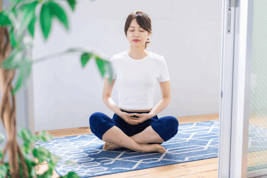 A woman sitting cross-legged on a yoga mat with closed eyes, practicing meditation :Breathing Exercise for Nerves