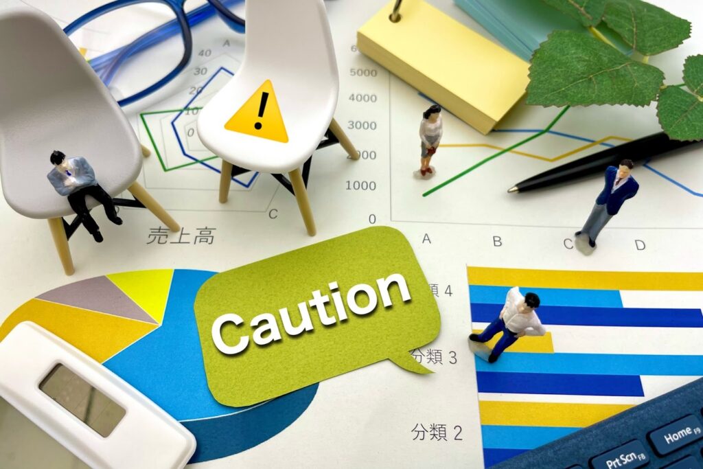 A desk scene with graphs, charts, sticky notes, chairs, and miniature figures, featuring a speech bubble with the word "Caution." Colorful data charts and the word "sales" are visible in the background : Body Scan Meditation