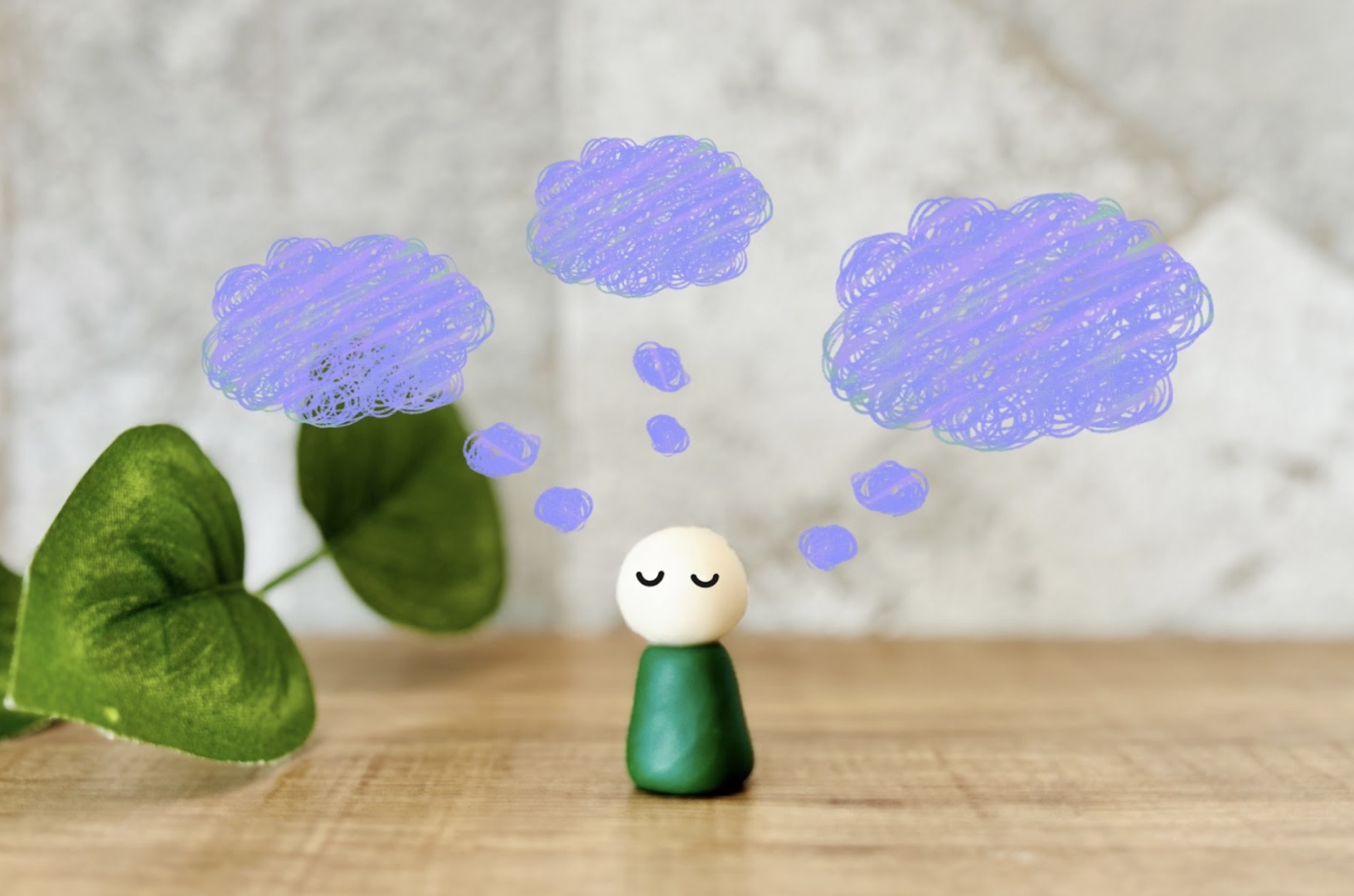 木のテーブルの上で目を閉じている小さな人形の上に、淡い紫色の雲のような思考のイメージが浮かんでいる。心の中の静けさやマインドフルネスを表現している：初心者のための瞑想