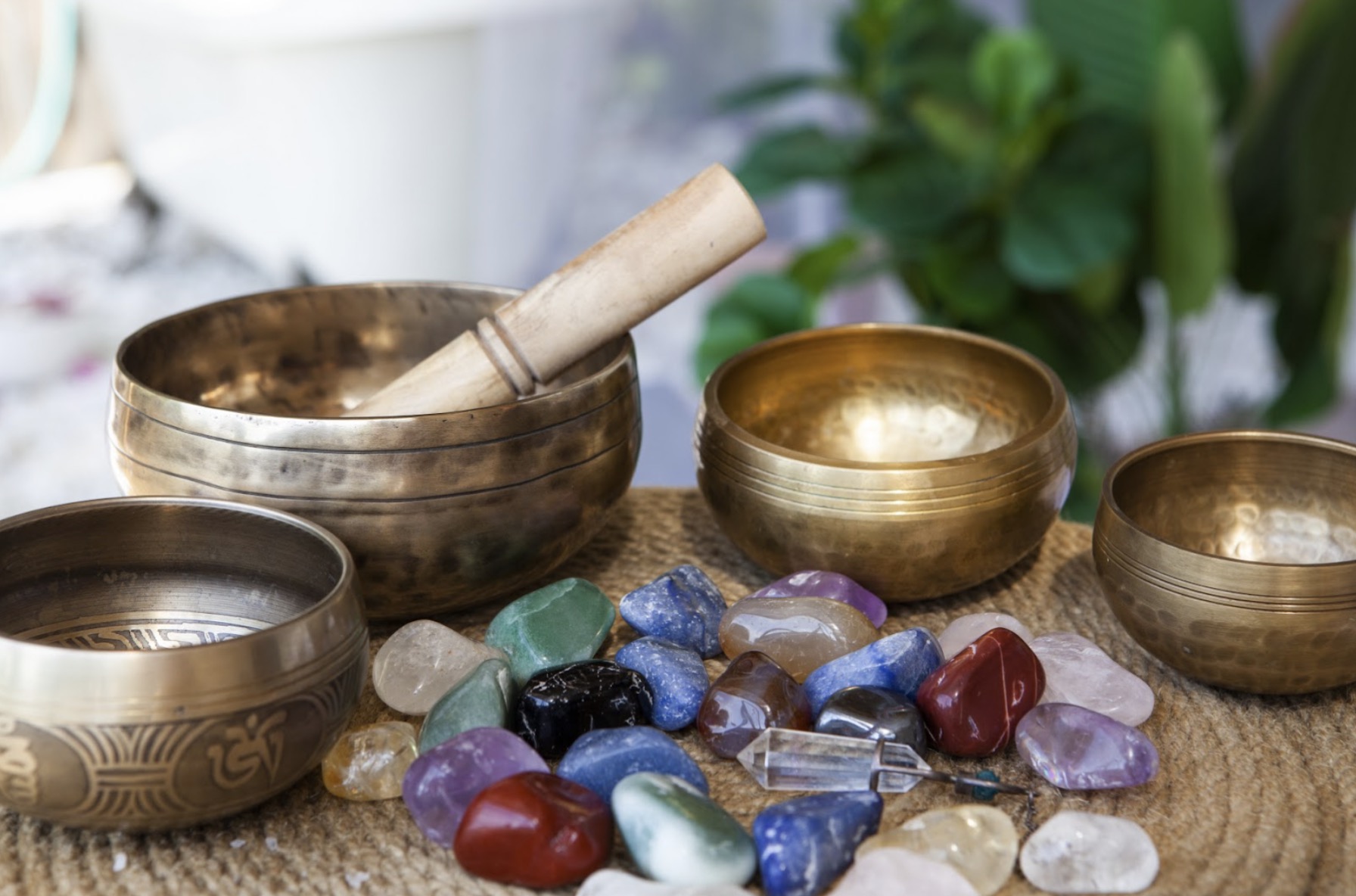 Several singing bowls and colorful crystals placed on a table, symbolizing meditation, balance, and healing energy: Tibetan Singing Bowl