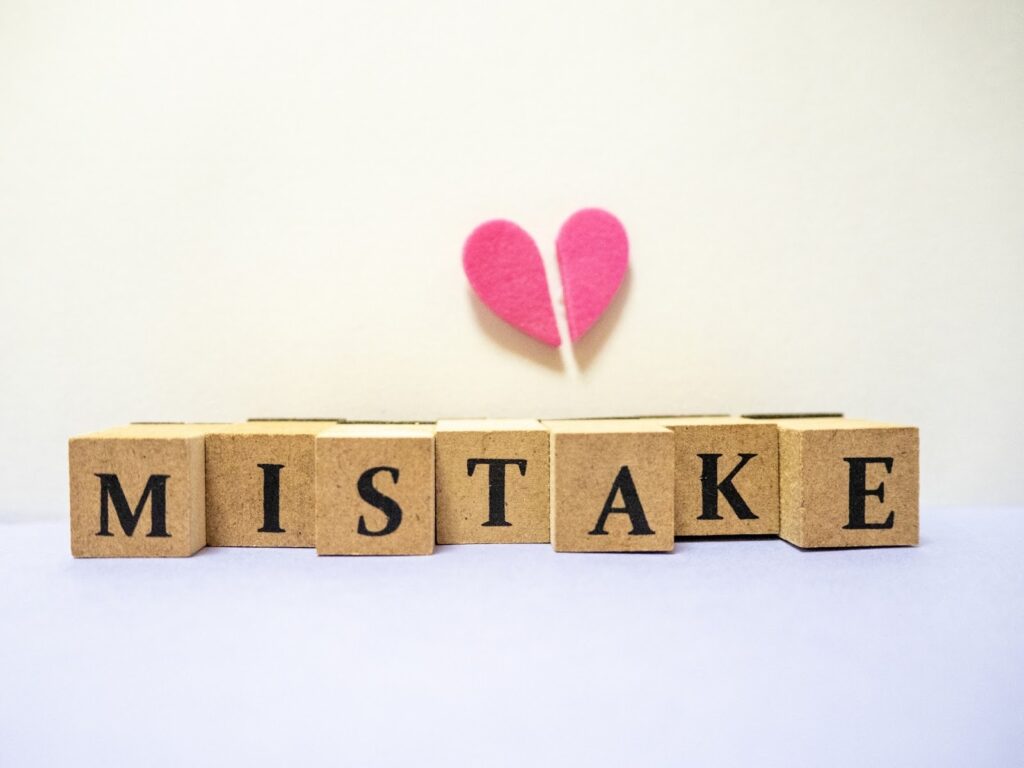 Wooden blocks spelling “MISTAKE” with a broken pink heart above them, symbolizing regret, emotional pain, or learning from failure: Meditation for Beginners
