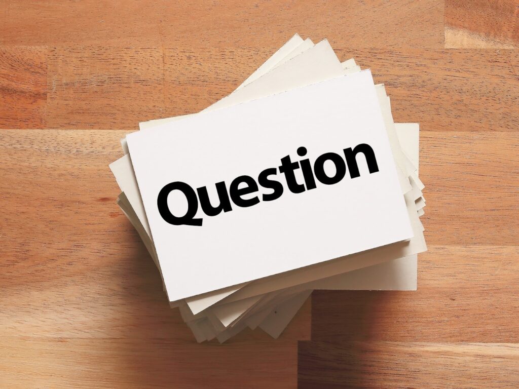 木製のテーブルの上に重ねられたカードの一番上に、「Question（質問）」と書かれた白いカードが置かれている：静けさの瞑想