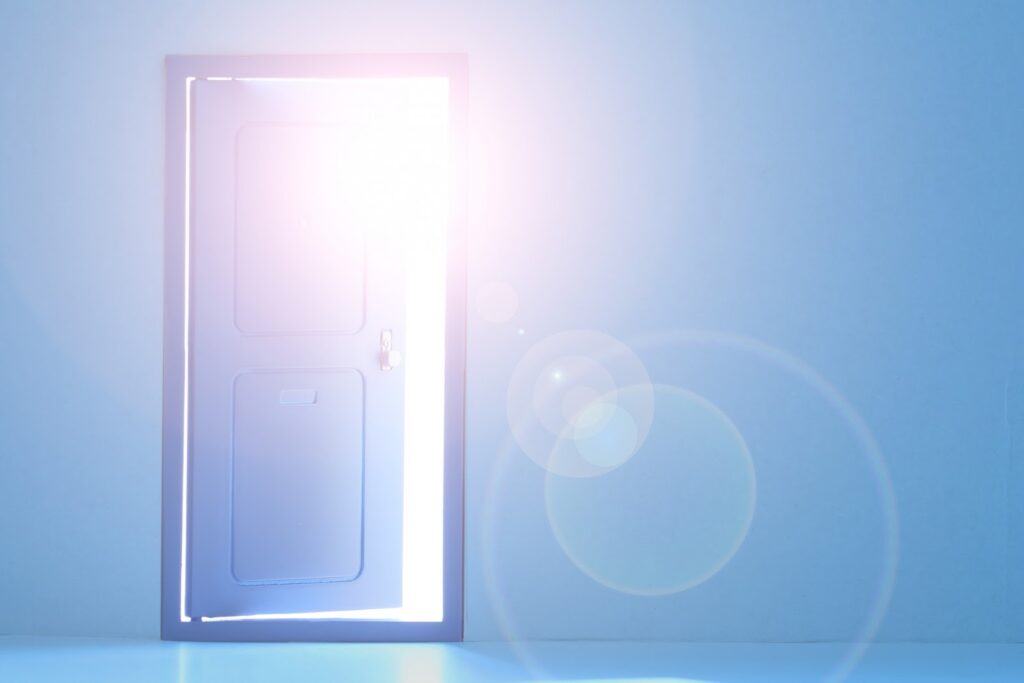 青い扉が少し開き、外から明るい光が差し込んで室内を照らしている:慈愛の瞑想